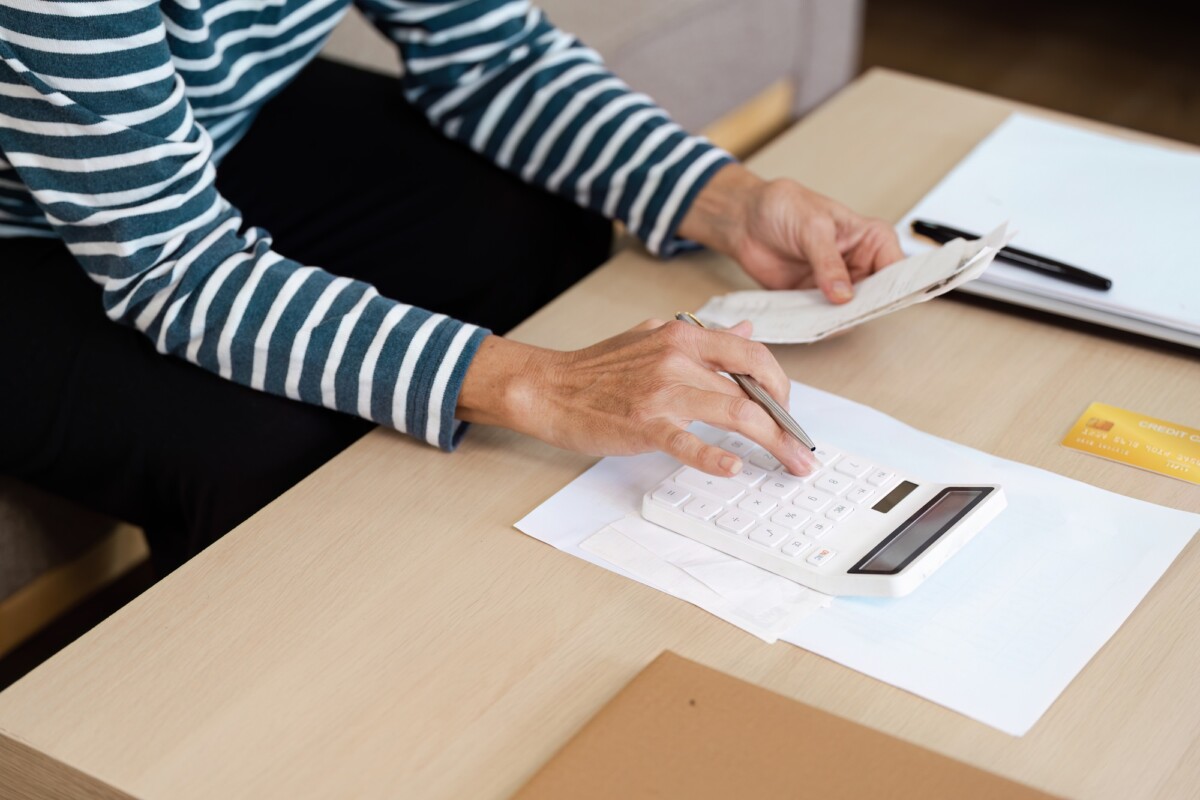 Senior Calculating financial at Home with Calculator and Receipt on Wooden Table, Managing Personal