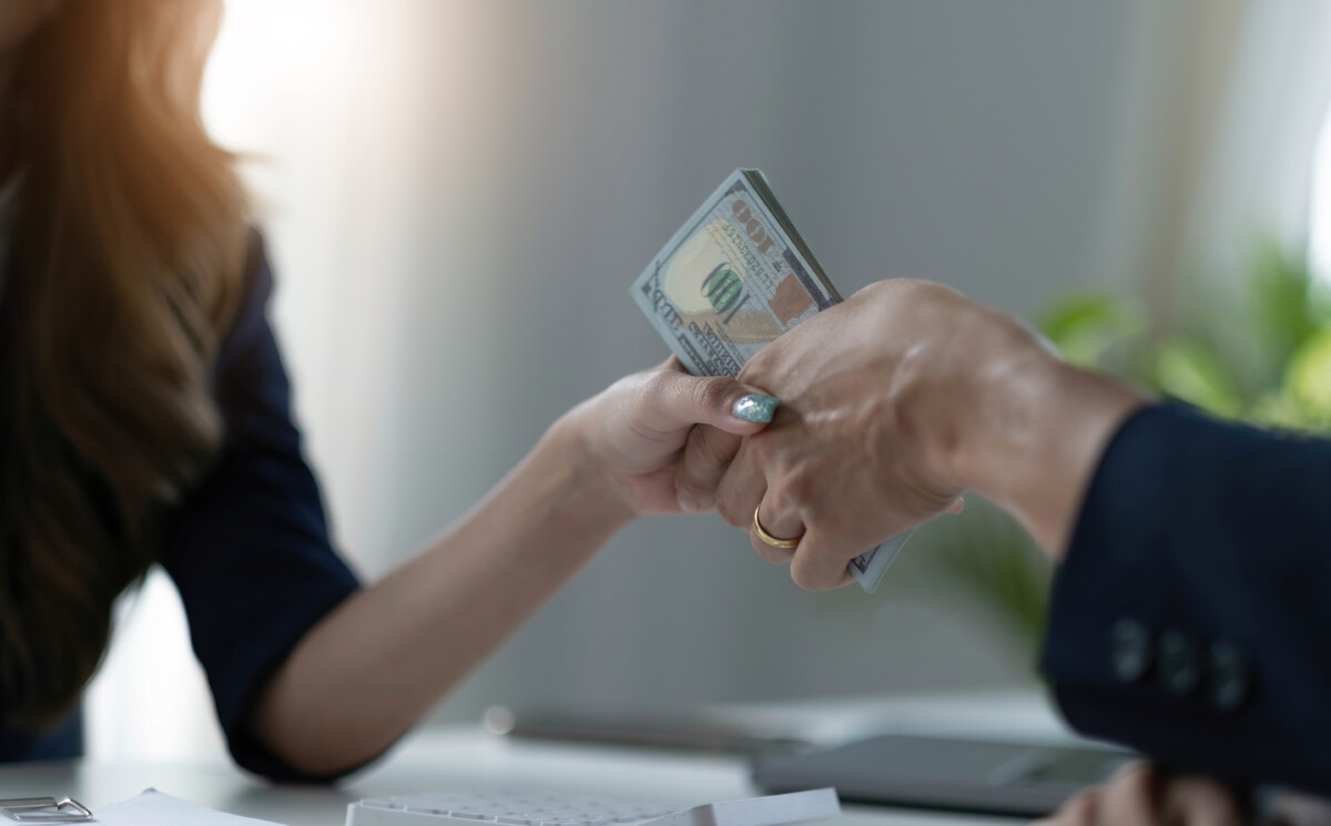 A female lawyer or business legal consultant receives a bribe or tribute from her client in the office. Corruption concept. cropped and close-up image