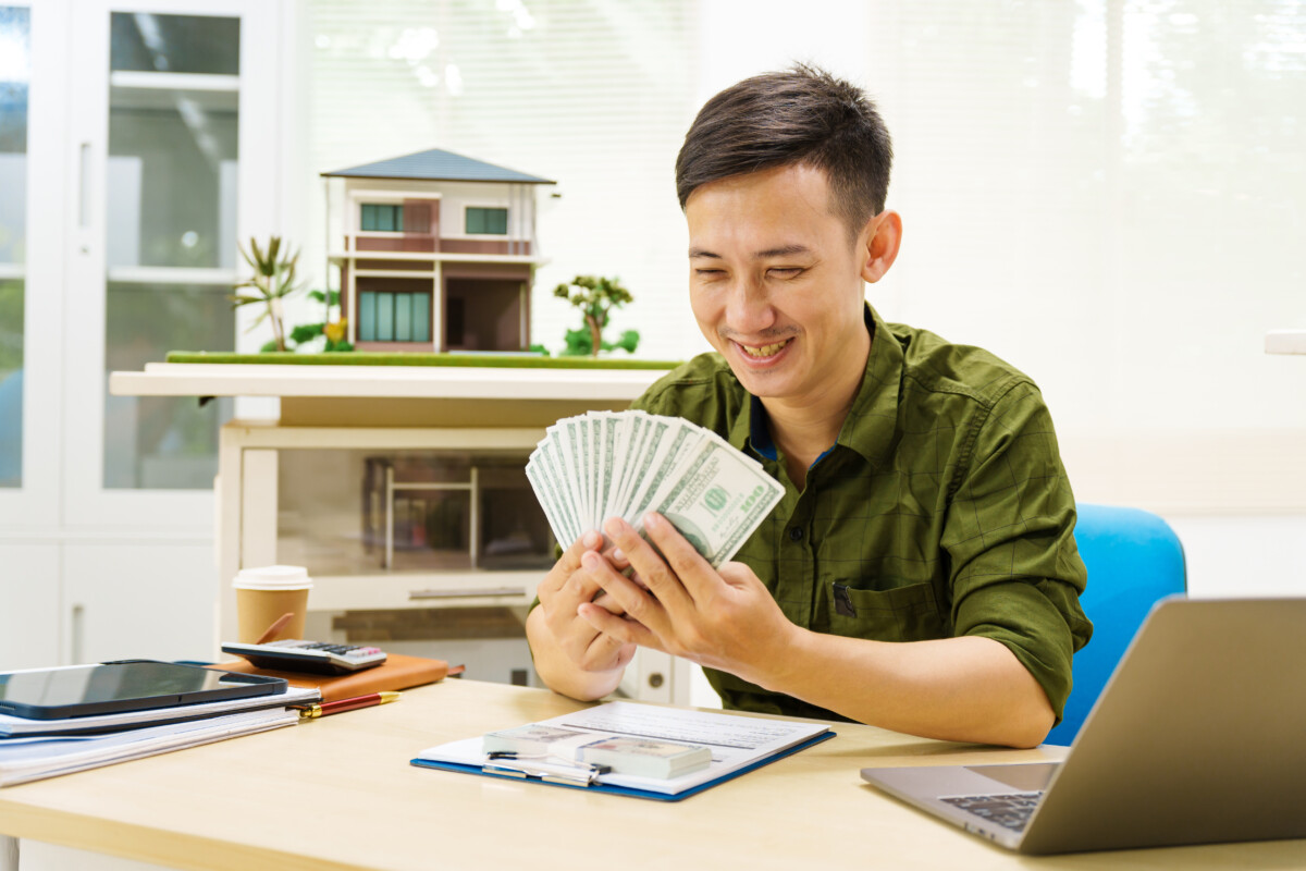 Asian businessman works alone at his desk, surrounded by a lapto