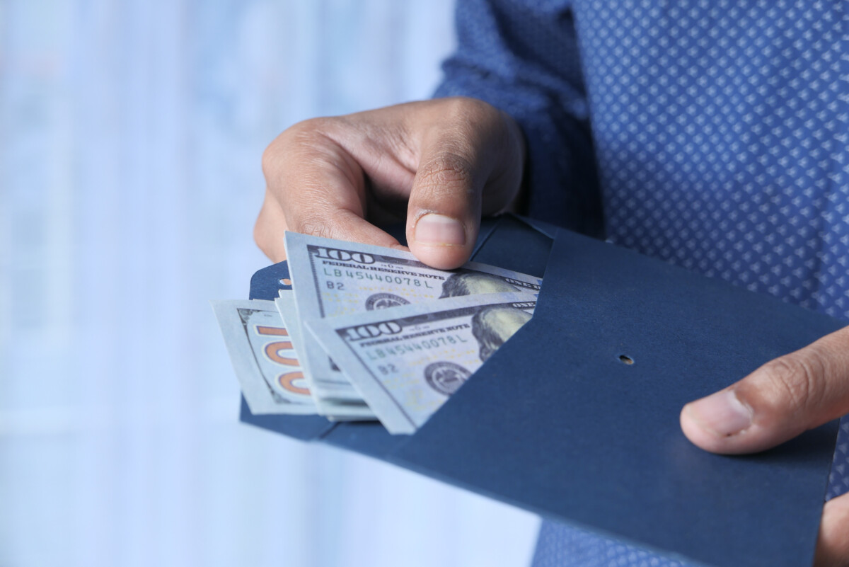 person hand putting cash in a envelope.