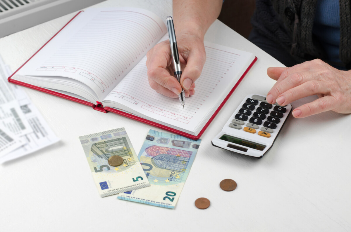 The pensioner calculates utility costs. Elderly woman hands are counting finances on a calculator